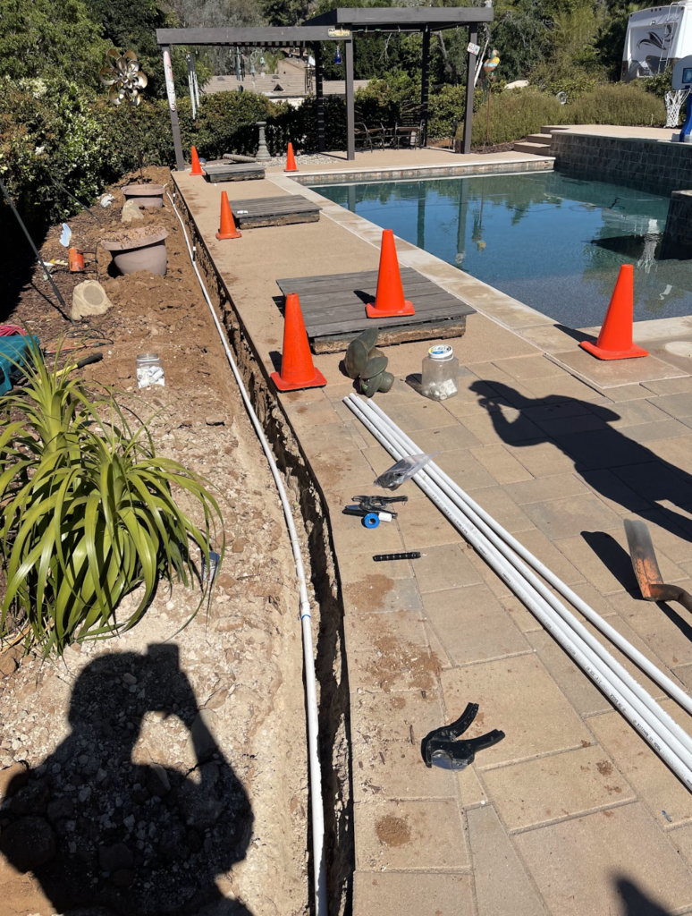 hole along the side of side walk and pipes being installed for landscape irrigation system